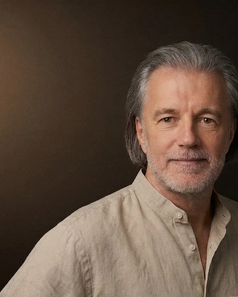 Alexander Renner im Leinenhemd vor dunkelbraunem Studiohintergrund